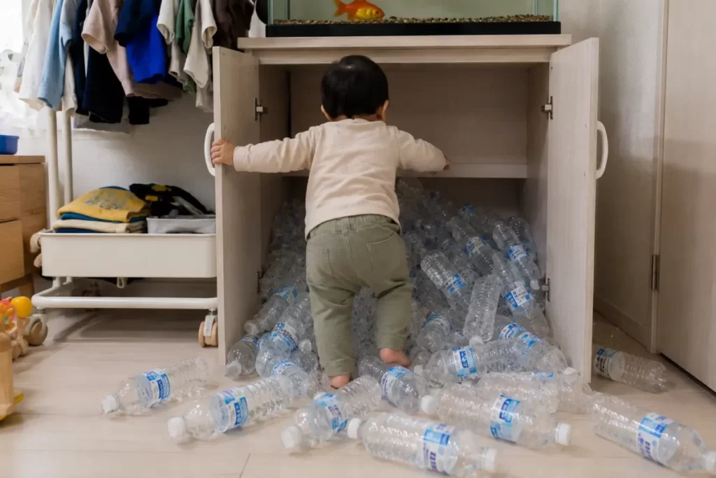 1歳児が収納から水のペットボトルを散らかす様子の写真